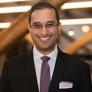 a man with glasses in a suit smiling