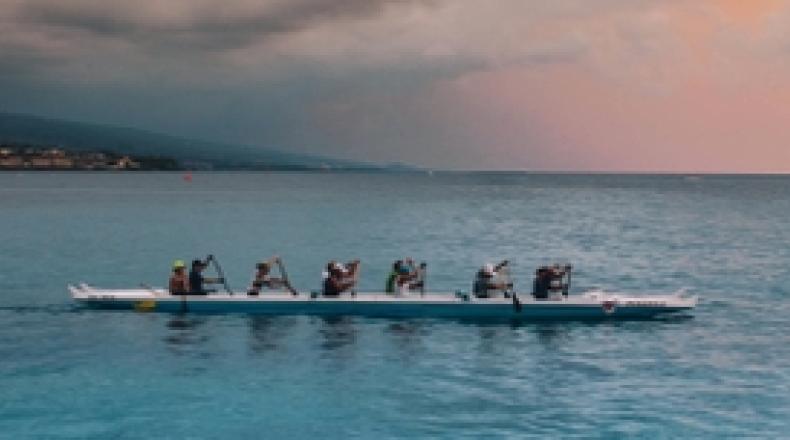 A team rowing a long canoe