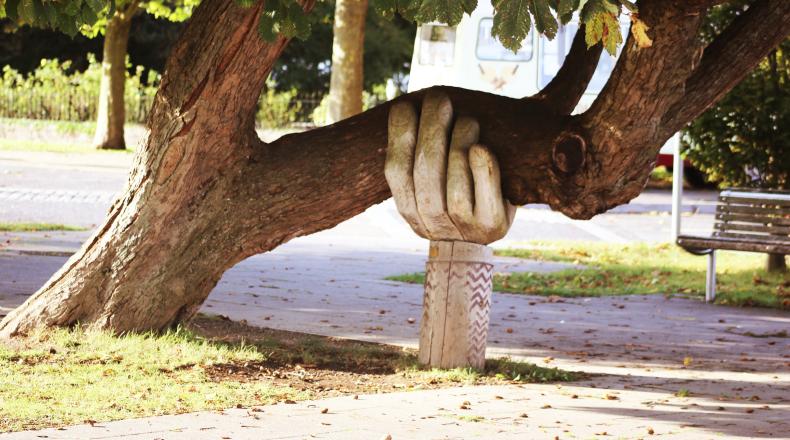a large carved hand holding up a tree