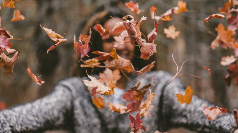 woman throwing leaves in air