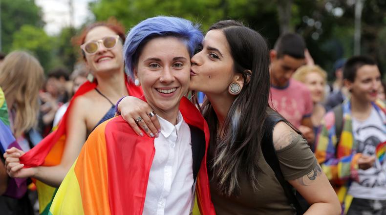 two women kissing with a rainbow cloth around their shoulders