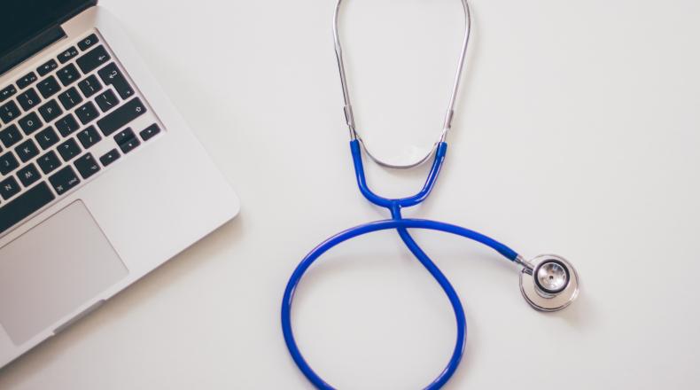 a blue stethoscope next to a laptop