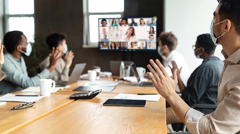 people in a meeting watching other attendees on a screen