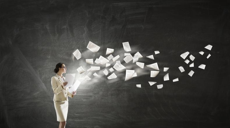 business woman in white suit with papers flying out of her hands