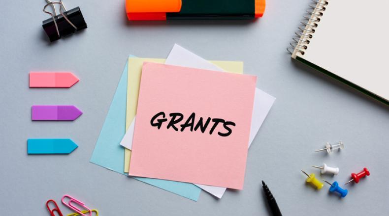 The word grants written on a notepaper on business office desktop.