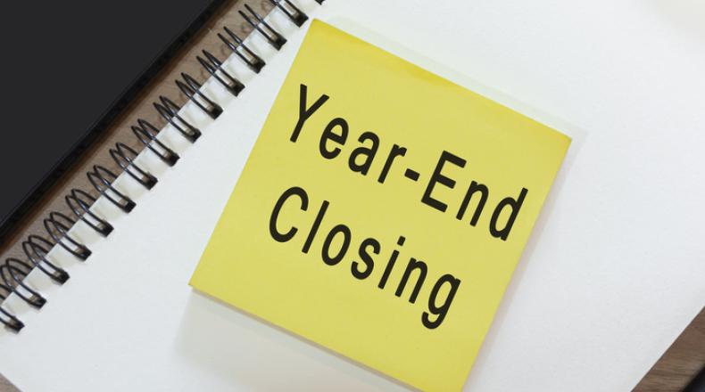Text on yellow note with notepad on wooden desk - Year-end closing stock photo