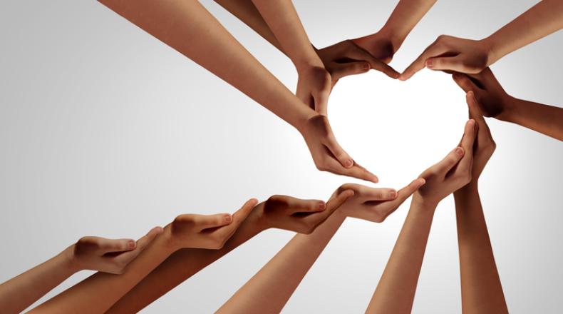 Unity And Togetherness; multi-cultural hands and arms extended to create a heart shape stock photo