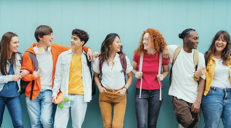 Diverse young people standing together in front of blue wall