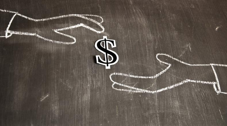 white chalk drawing on black background of one hand depositing a dollar sign into another hand