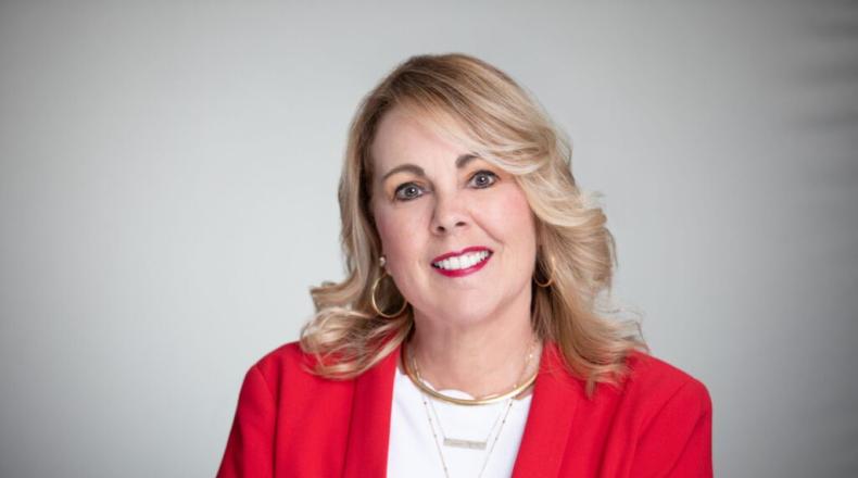 a woman, Rebecca Powell, smiling and wearing a red jacket