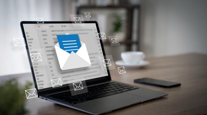 floating envelope icons in front of open laptop on a wooden desk