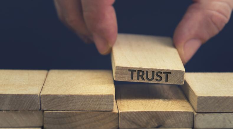 Building Trust concept, stack of wooden blocks with one with word trust being placed into open slot in stack