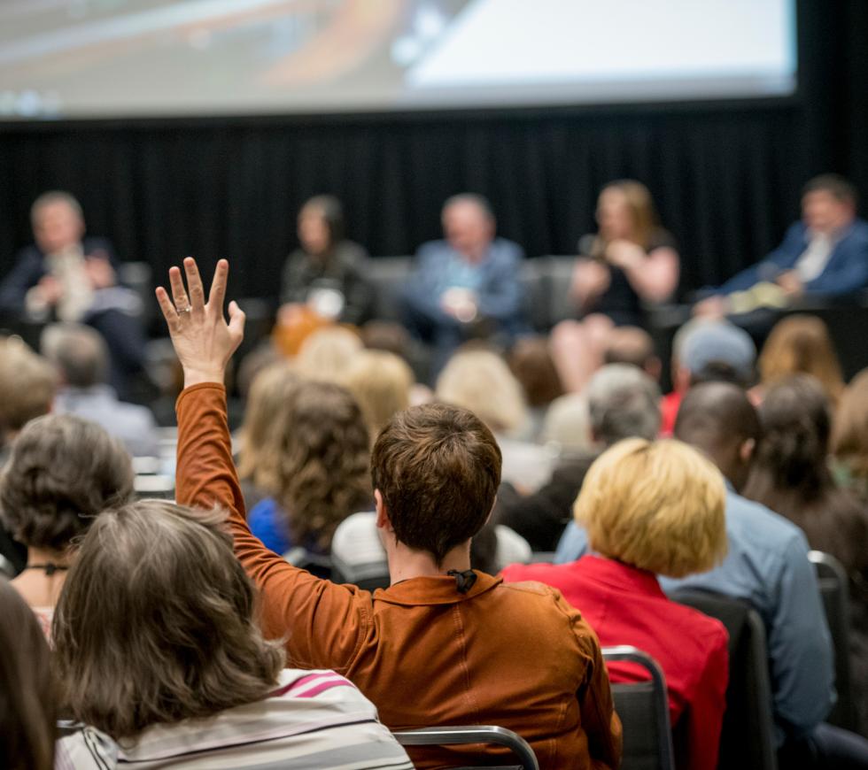 Man raising his hand to ask a question during a conference session