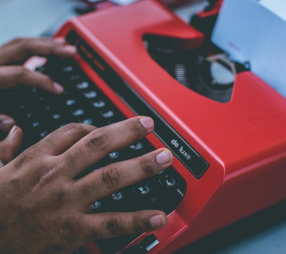 someone typing on a red typewriter