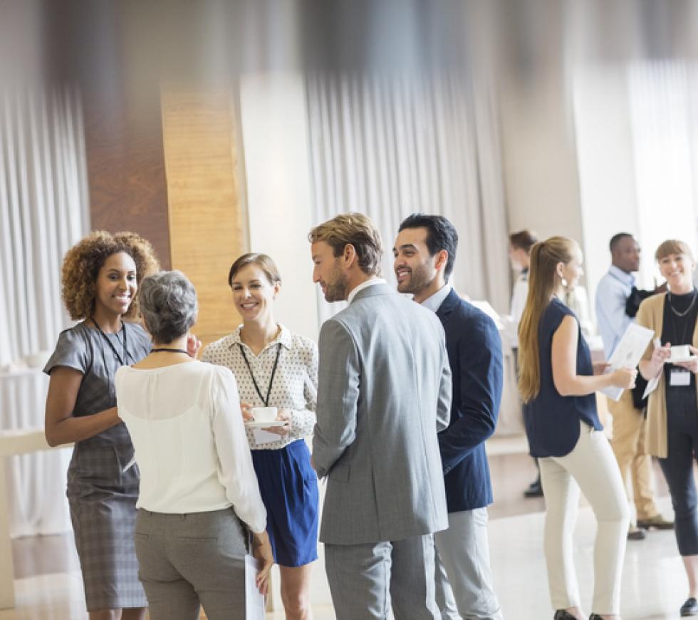 Group of business people standing in hall, smiling and talking together stock photo