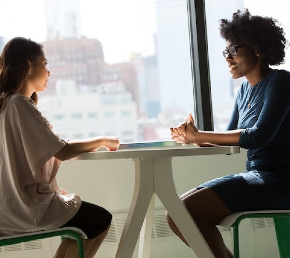 two women sitting beside table and talking