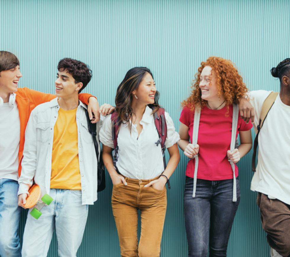 Diverse young people standing together in front of blue wall