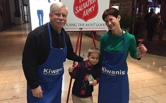 Dr. F. Duke Haddad and a woman in Kiwanis aprons at a Salvation Army donation location with a child donating money.