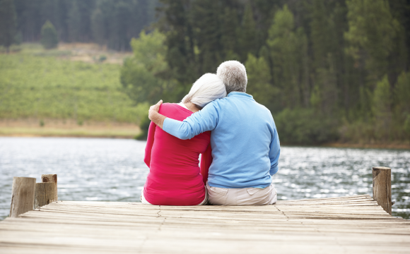 Senior couple sitting on a dock by a lake
