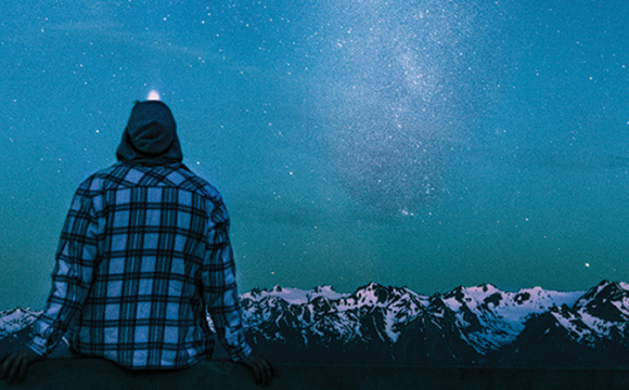 person sitting looking at the night sky with stars