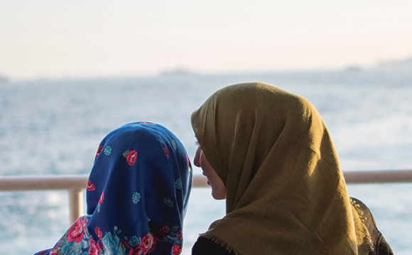 two muslim women sitting on a bench talking