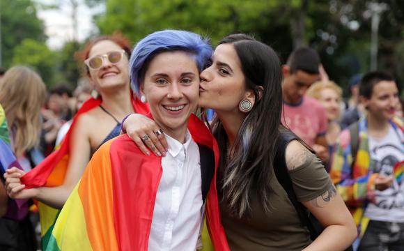 two women kissing with a rainbow cloth around their shoulders