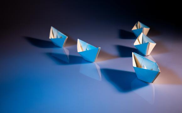 paper ships on a black and blue background