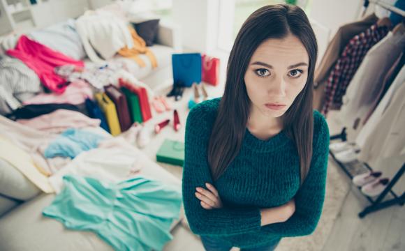 high angle point of view of unhappy girl with clothes behind her