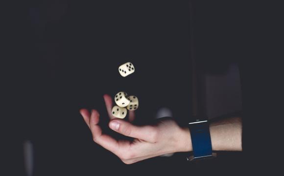 hand throwing dice in the air with a black background
