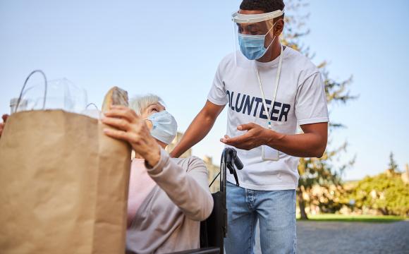 young man helping an elderly woman with her grocery bags