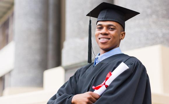 young black man in a cap and gown with a diploma