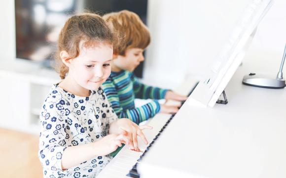 two little kids a boy and a girl playing the piano