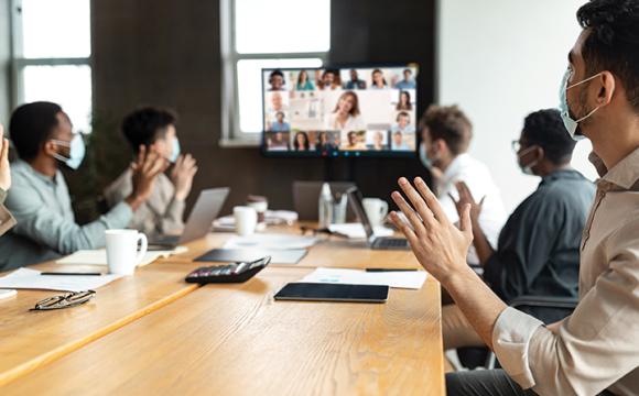 people in a meeting watching other attendees on a screen