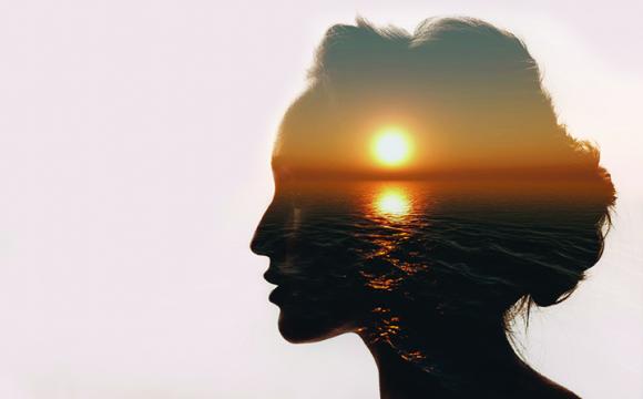 silhouette of a woman with a sunset over water