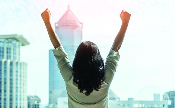 woman in a city with her arms raised