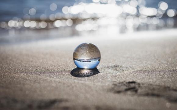 clear glass ball sitting on sand