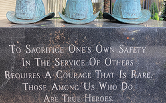 fireman hats sitting on a memorial stone with words engraved