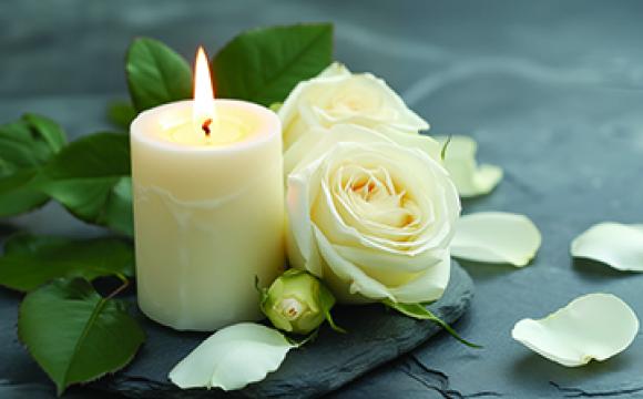 white rose next to a burning candle