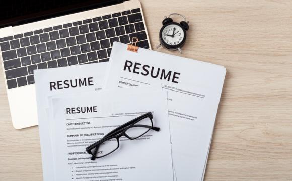 Resumes on laptop with glasses resume review stock photo