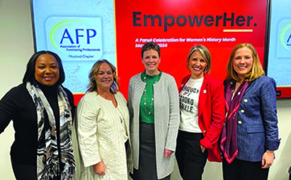 group of women in front of sign with empower her