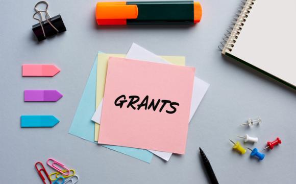 The word grants written on a notepaper on business office desktop.