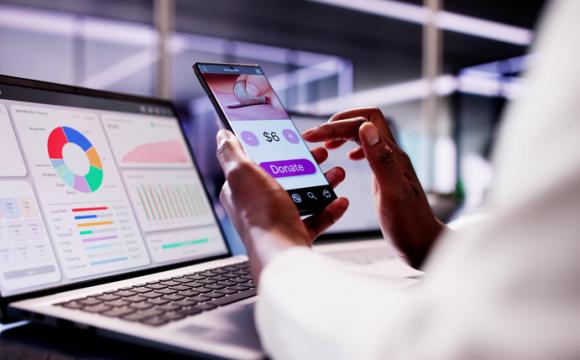 African American woman using smartphone app to donate money online, supporting charities and investing stock photo