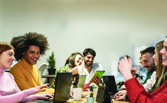 group of young people at a table with laptops