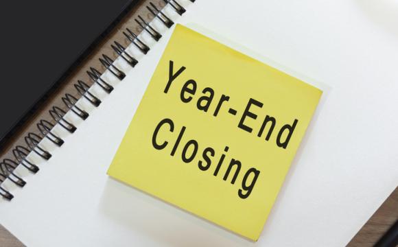 Text on yellow note with notepad on wooden desk - Year-end closing stock photo