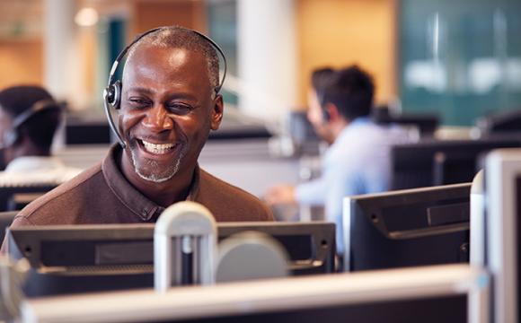 african american man laughing and smiling with a headset on sitting at a computer