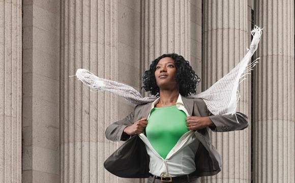 black woman opening her shirt to show a green shirt underneath with her jacket open and scarf blowing in the wind