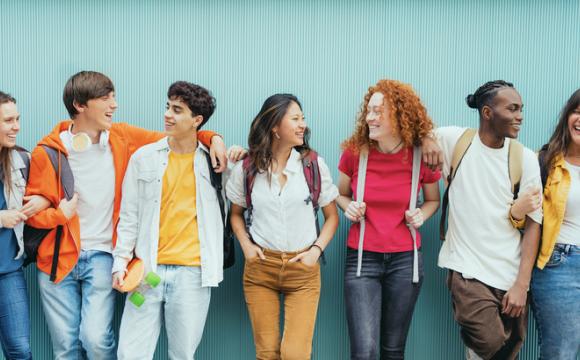 Diverse young people standing together in front of blue wall