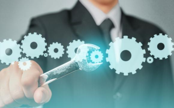  business man holding wrench up to image of gear wheels