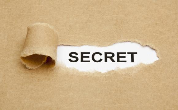 Secret Concept stock photo; torn brown paper reveals word secret in black lettering on white background