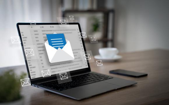 floating envelope icons in front of open laptop on a wooden desk